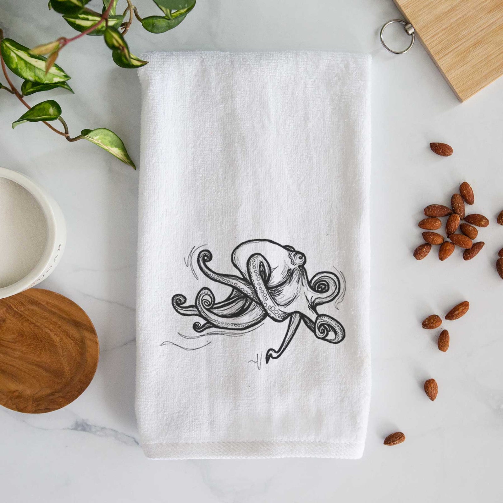 White hand towel printed with a black ink illustration of a giant Pacific octopus with curling tentacles.