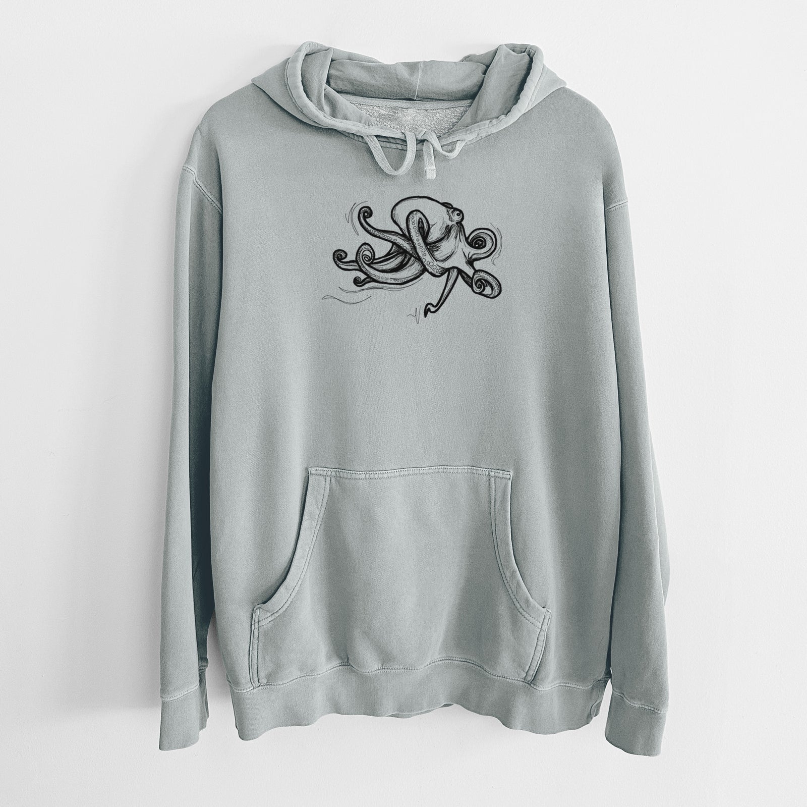 Sage green pigment dyed hoodie laid flat, printed with a black ink illustration of a giant Pacific octopus with curling tentacles.