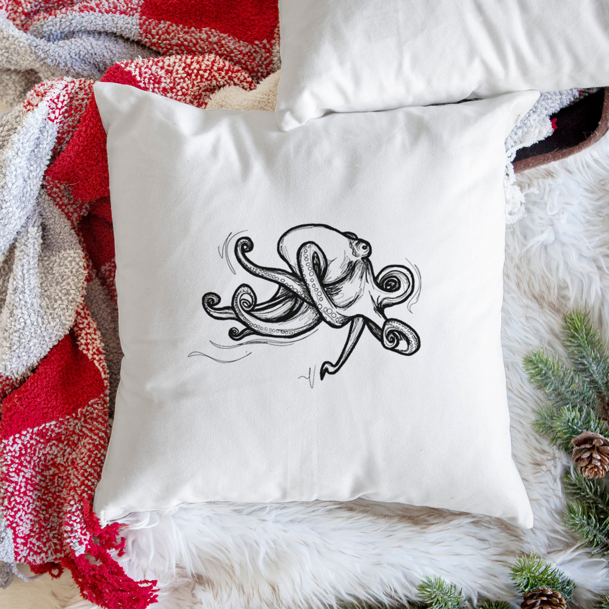 White pillow cover printed with a black ink illustration of a giant Pacific octopus with curling tentacles, on a woven chair.
