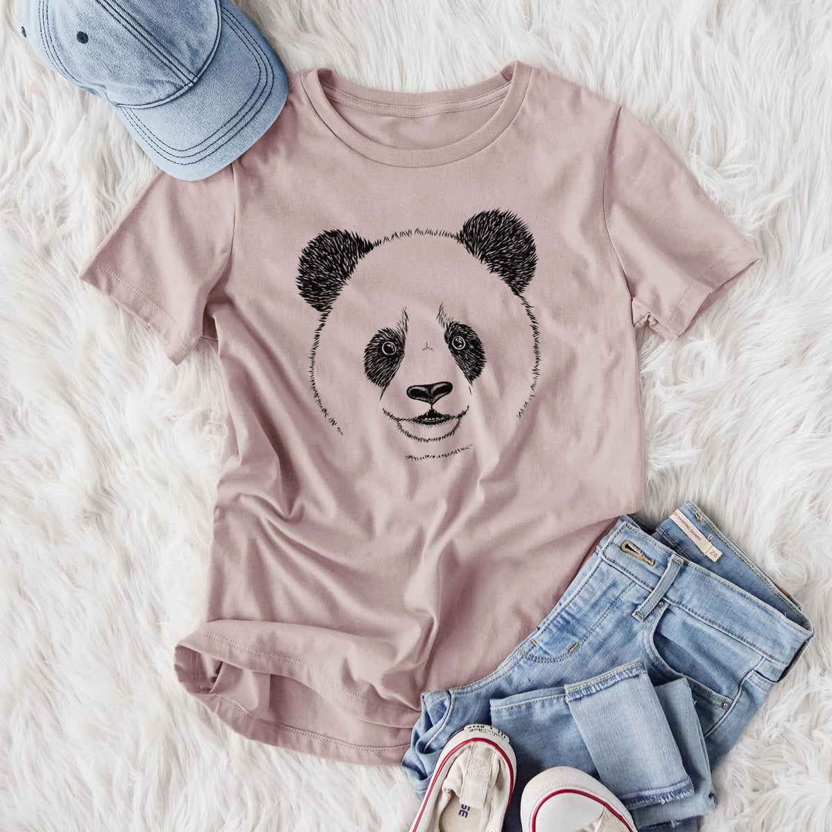 Women's relaxed fit cotton t-shirt printed with a black ink portrait of a smiling giant panda's face, styled flat on a white faux fur rug with jeans.