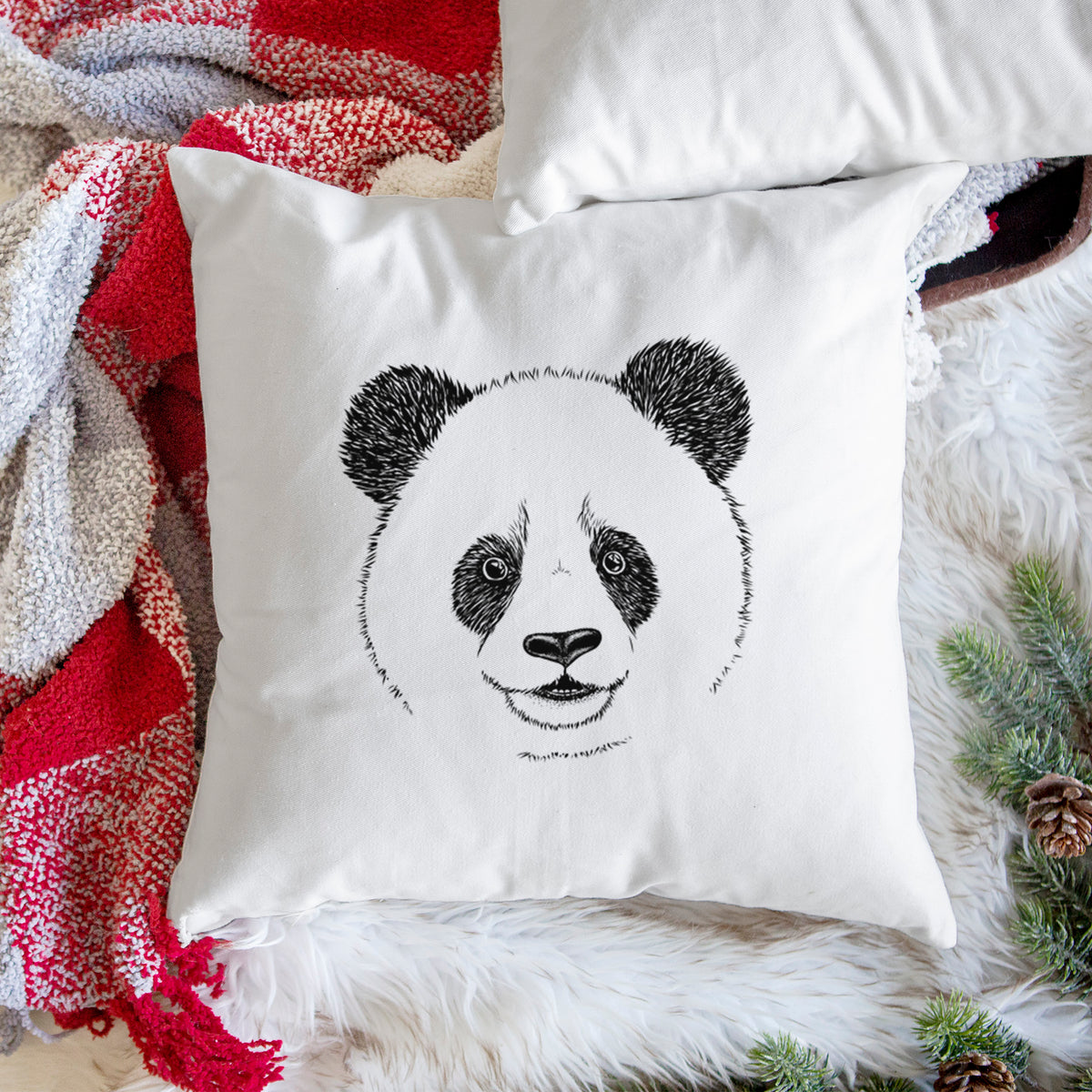 White pillow cover printed with a black ink portrait of a smiling giant panda's face, on a woven chair.