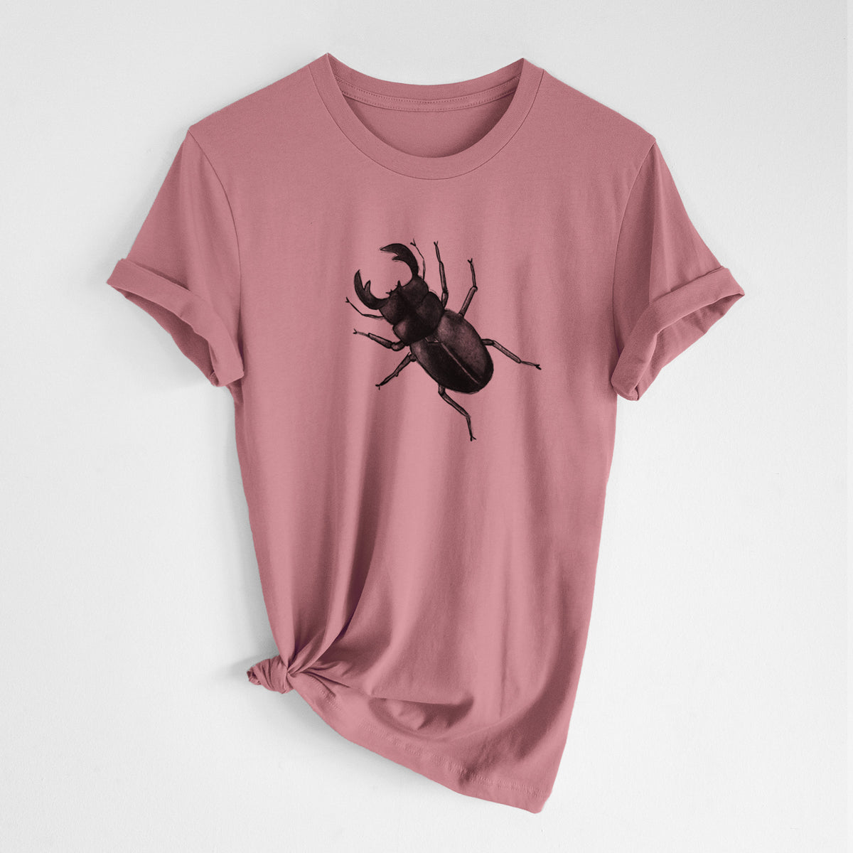 Mauve pink lightweight cotton t-shirt laid flat with the sleeves rolled, printed with a detailed black ink illustration of a giant stag beetle with large jaws, seen from above.