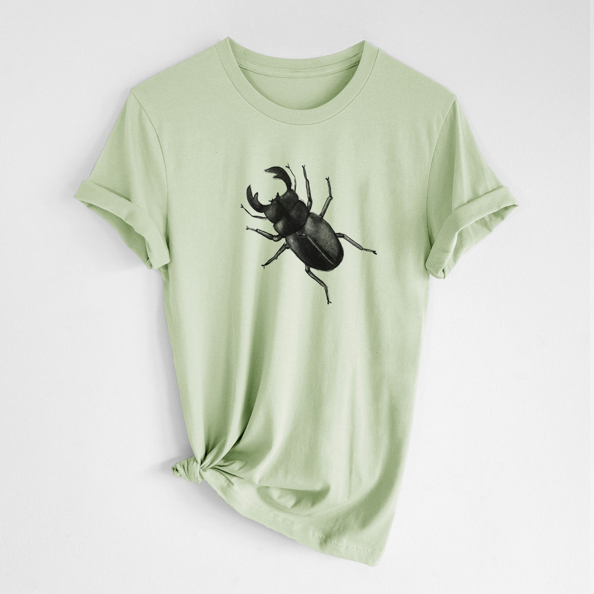 Spring green lightweight cotton t-shirt laid flat with the sleeves rolled, printed with a detailed black ink illustration of a giant stag beetle with large jaws, seen from above.