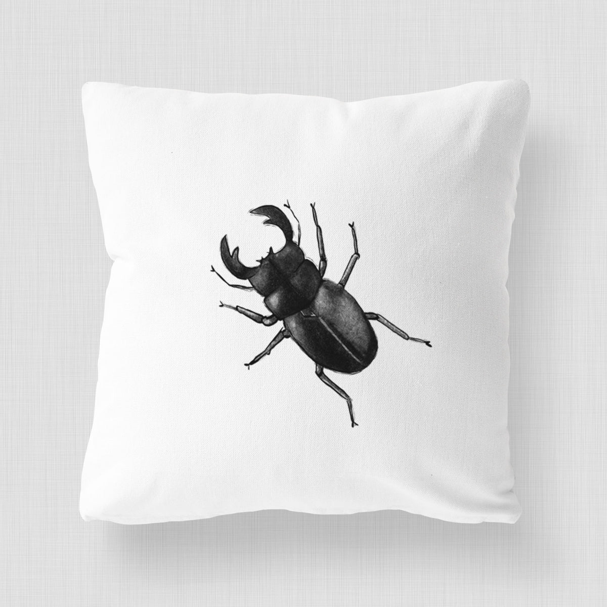 White pillow cover printed with a detailed black ink illustration of a giant stag beetle with large jaws, seen from above.