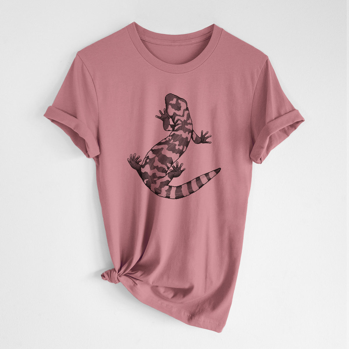 Mauve pink lightweight cotton t-shirt laid flat with the sleeves rolled, printed with a black ink illustration of a Gila monster with bold patterned skin.
