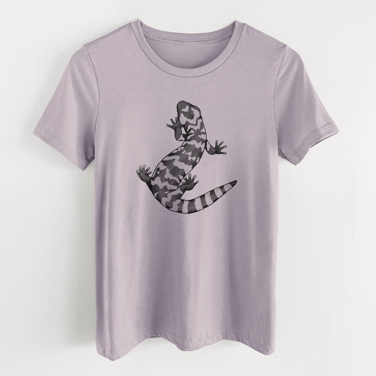 Light violet women's relaxed fit cotton t-shirt laid flat, printed with a black ink illustration of a Gila monster with bold patterned skin.