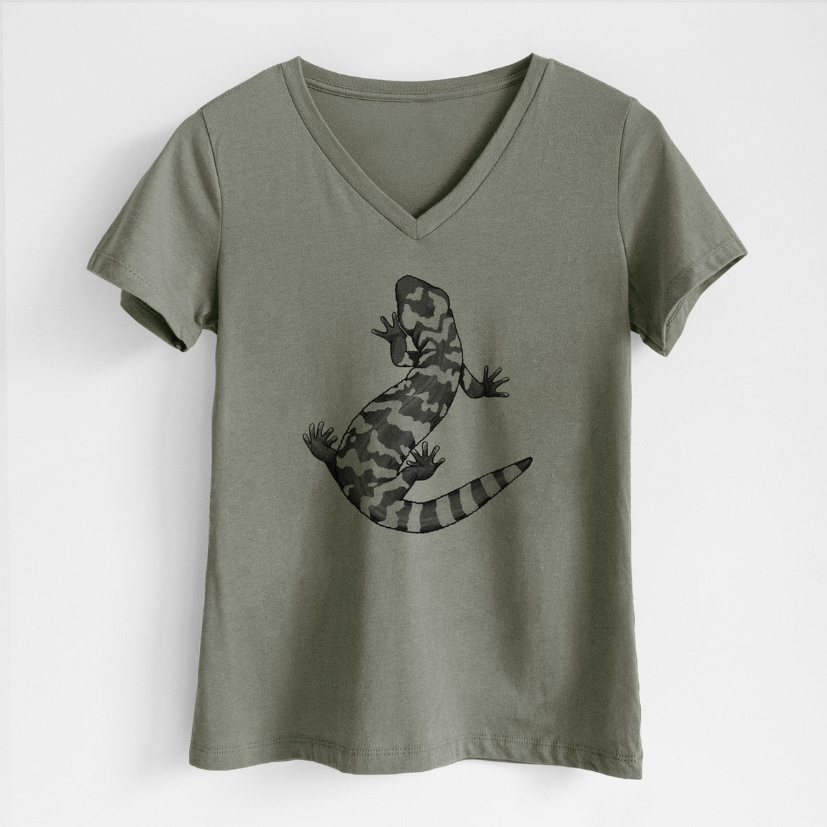 Military green women's relaxed fit cotton V-neck t-shirt laid flat, printed with a black ink illustration of a Gila monster with bold patterned skin.