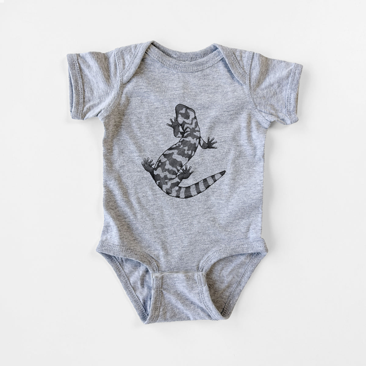 Grey baby bodysuit laid flat, printed with a black ink illustration of a Gila monster with bold patterned skin.
