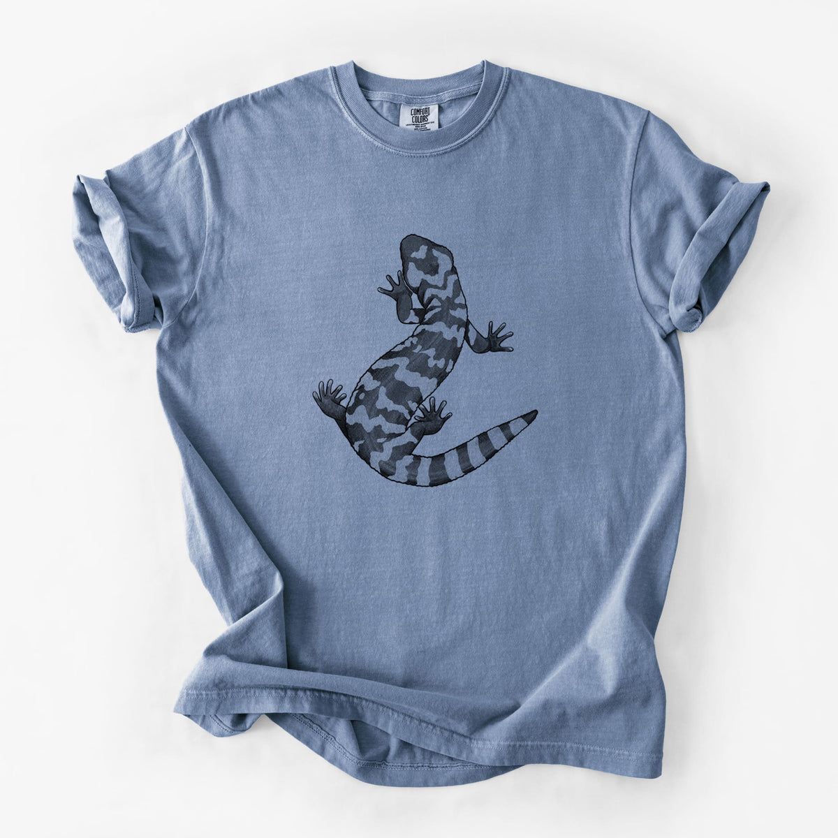 Blue jean Comfort Colors t-shirt laid flat, printed with a black ink illustration of a Gila monster with bold patterned skin.