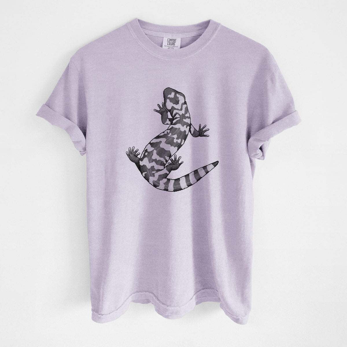 Orchid purple Comfort Colors t-shirt laid flat, printed with a black ink illustration of a Gila monster with bold patterned skin.