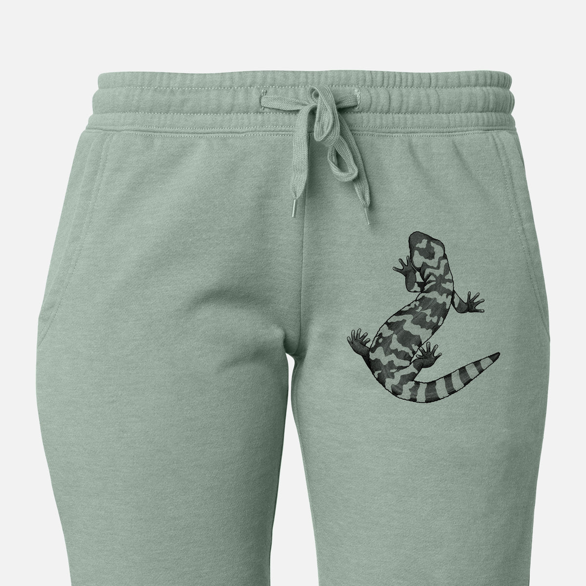 Front of sage green Cali Wave sweatpants, printed with a black ink illustration of a Gila monster with bold patterned skin on the leg.