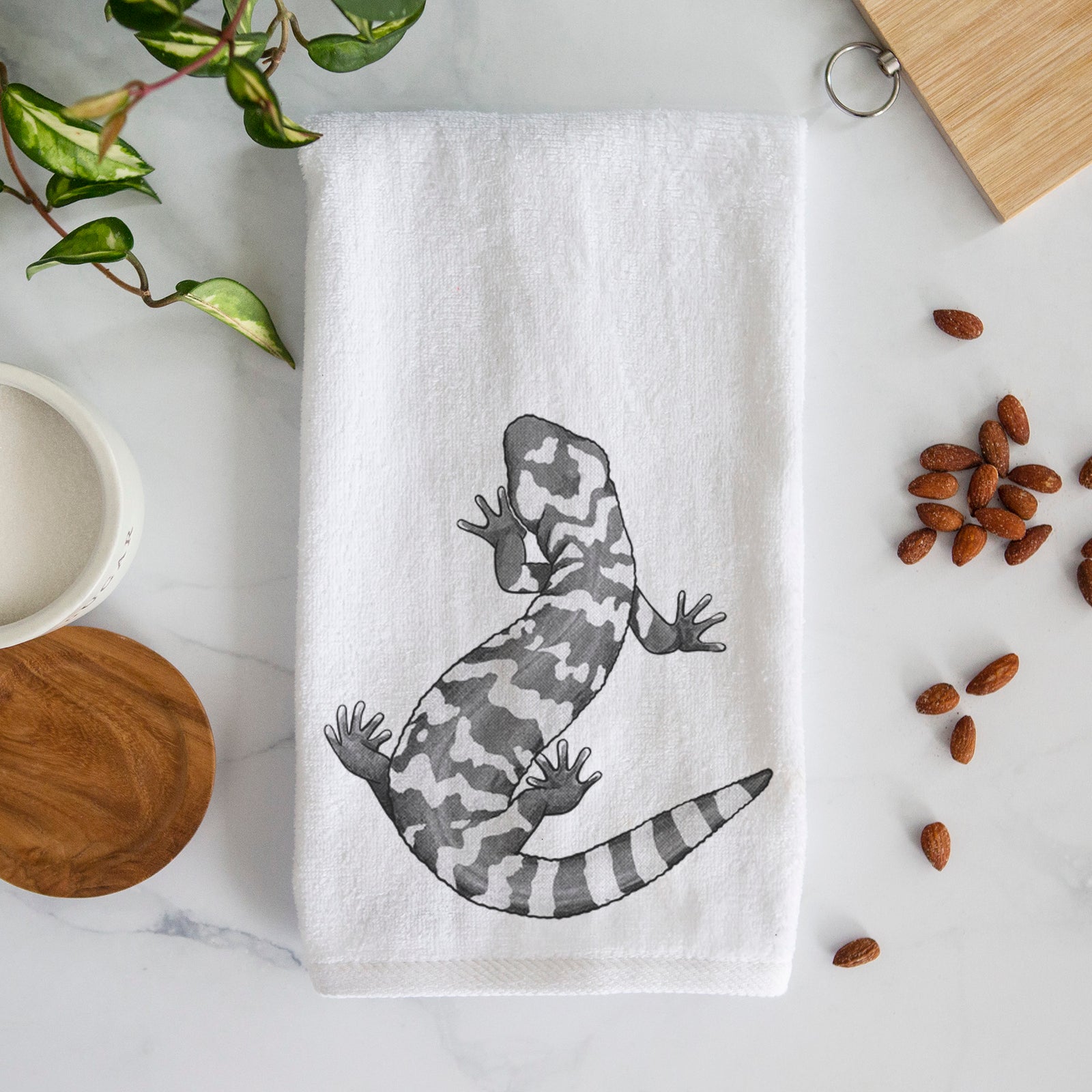 White hand towel printed with a black ink illustration of a Gila monster with bold patterned skin.