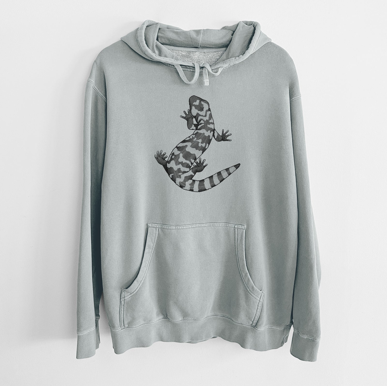 Sage green pigment dyed hoodie laid flat, printed with a black ink illustration of a Gila monster with bold patterned skin.