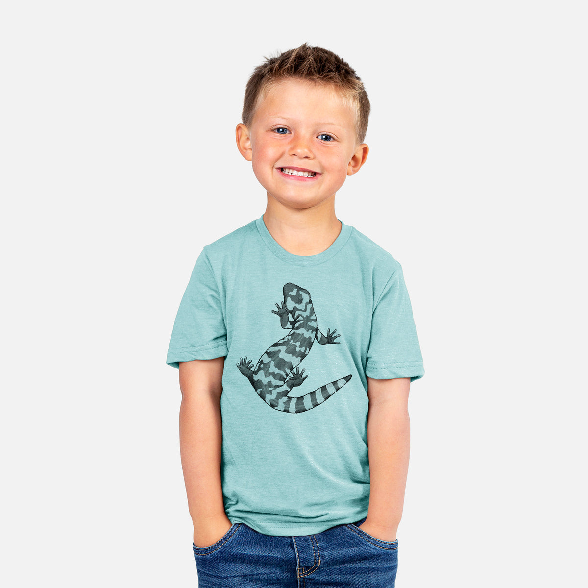 Smiling boy wearing a youth t-shirt printed with a black ink illustration of a Gila monster with bold patterned skin.