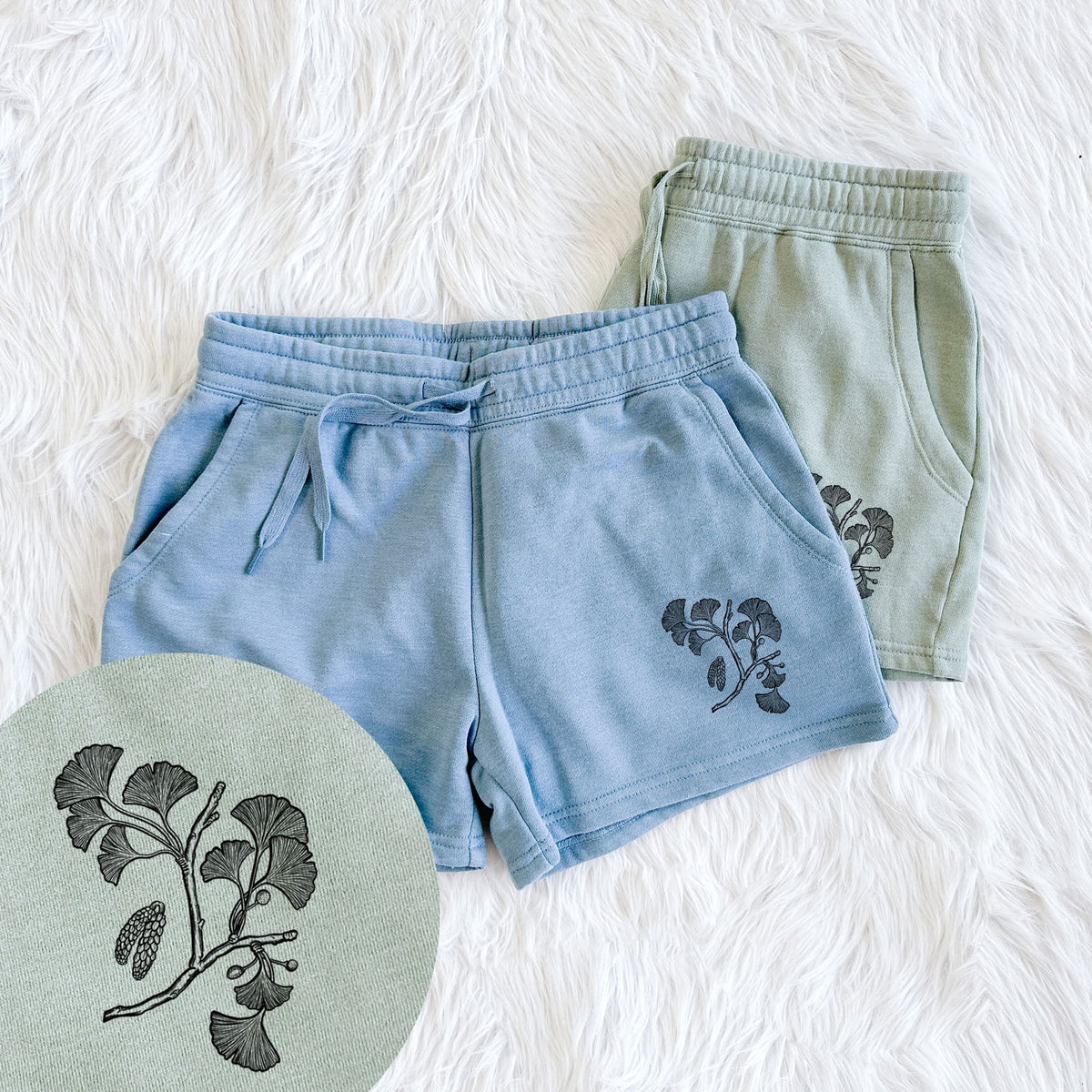 Two pairs of Cali Wave shorts in different colors printed with a black ink illustration of a ginkgo branch with fan-shaped leaves, with a close-up of the print.