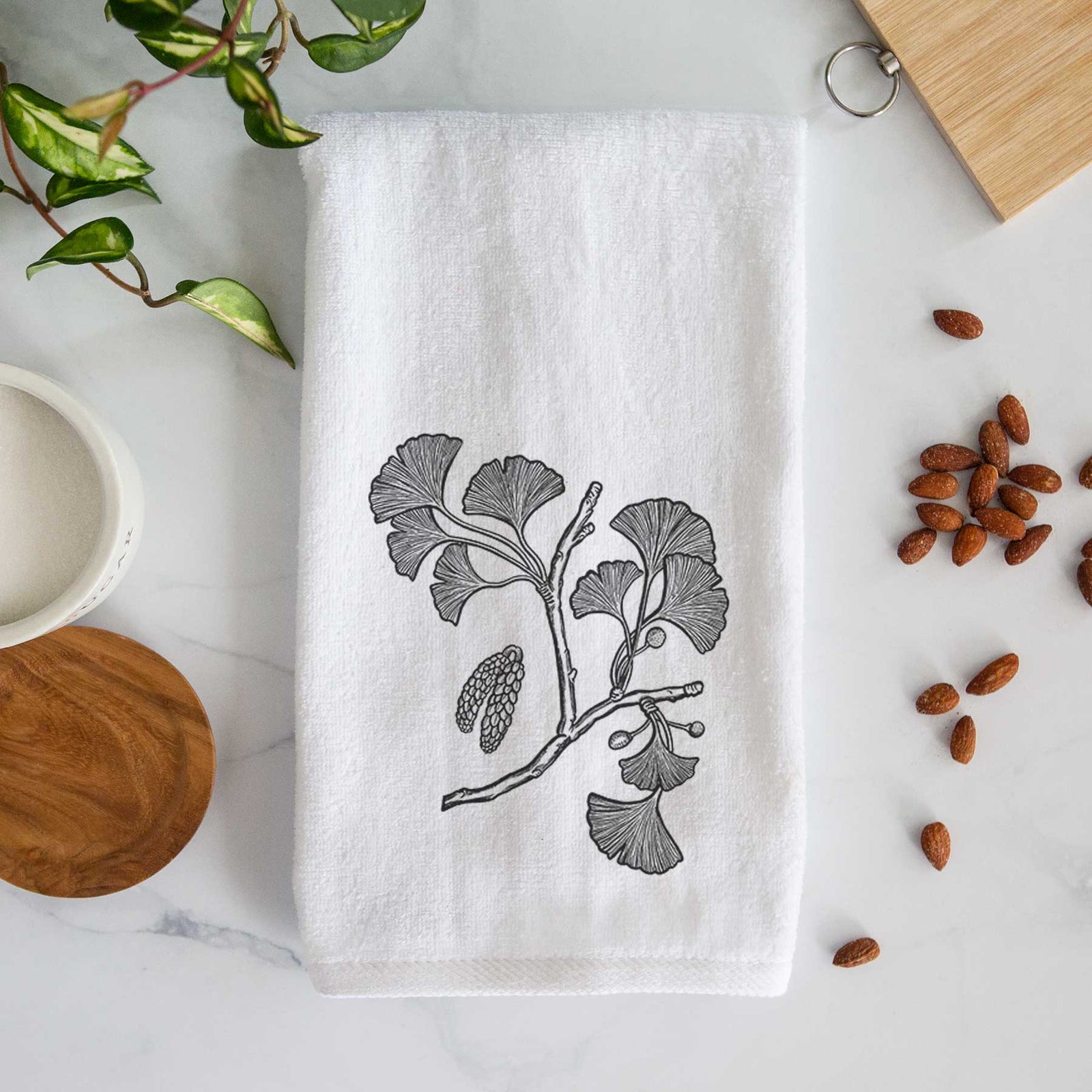 White hand towel printed with a black ink illustration of a ginkgo branch with fan-shaped leaves.