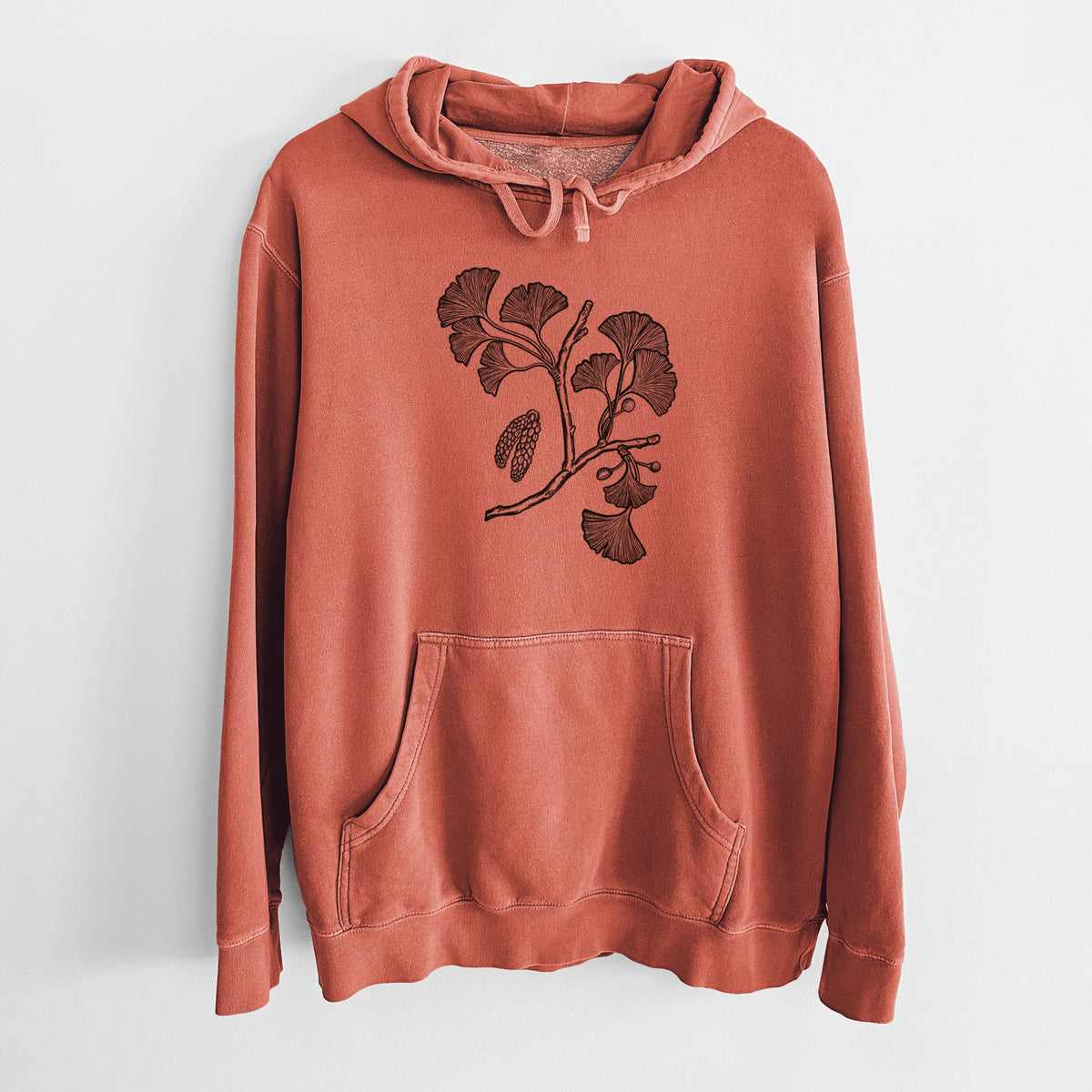 Amber orange pigment dyed hoodie laid flat, printed with a black ink illustration of a ginkgo branch with fan-shaped leaves.
