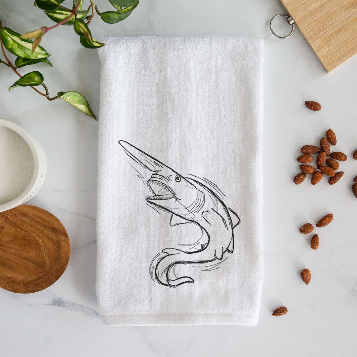 White hand towel printed with a black ink illustration of a goblin shark with its long snout, swimming in a curve.