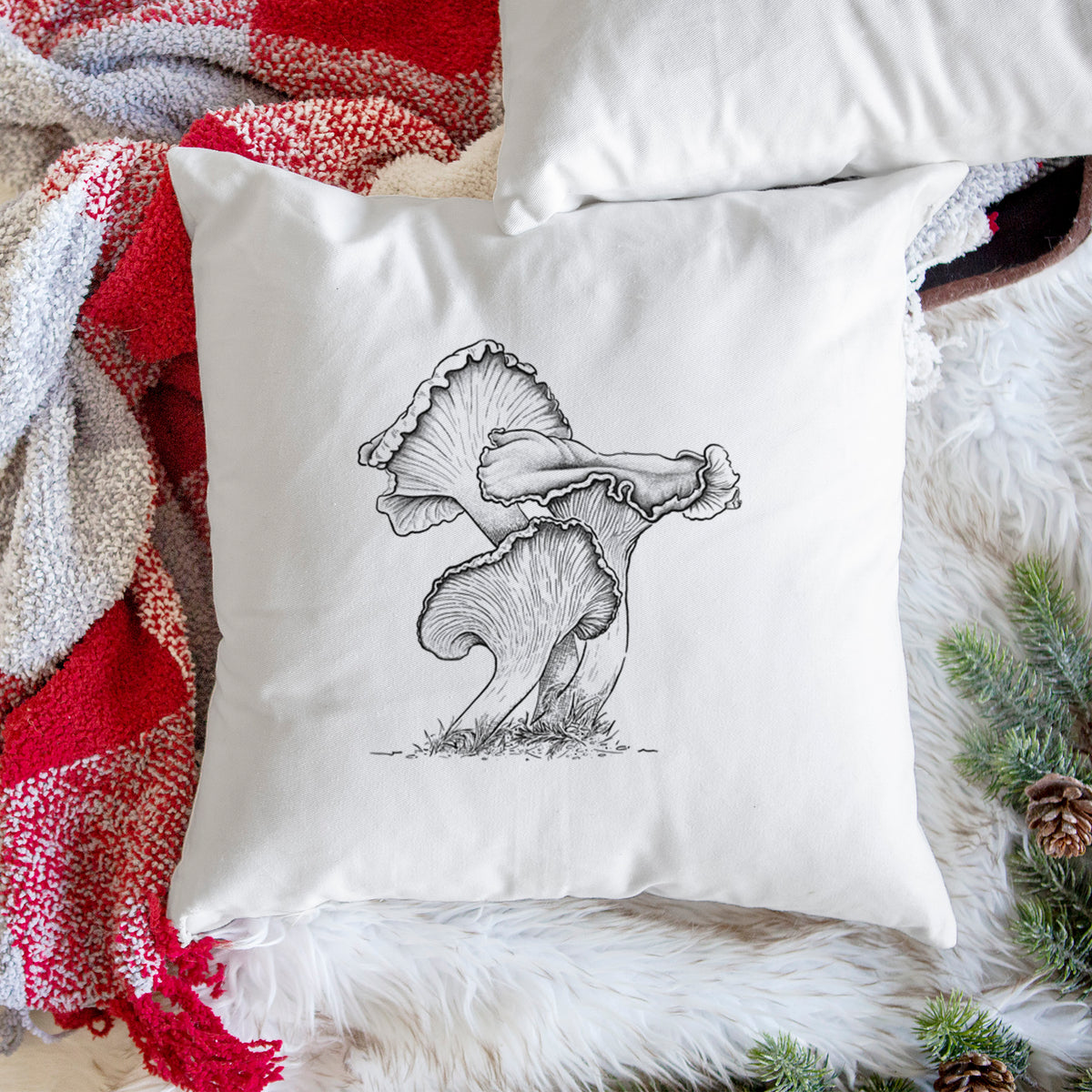 White pillow cover printed with a detailed black ink illustration of golden chanterelle mushrooms, on a woven chair.
