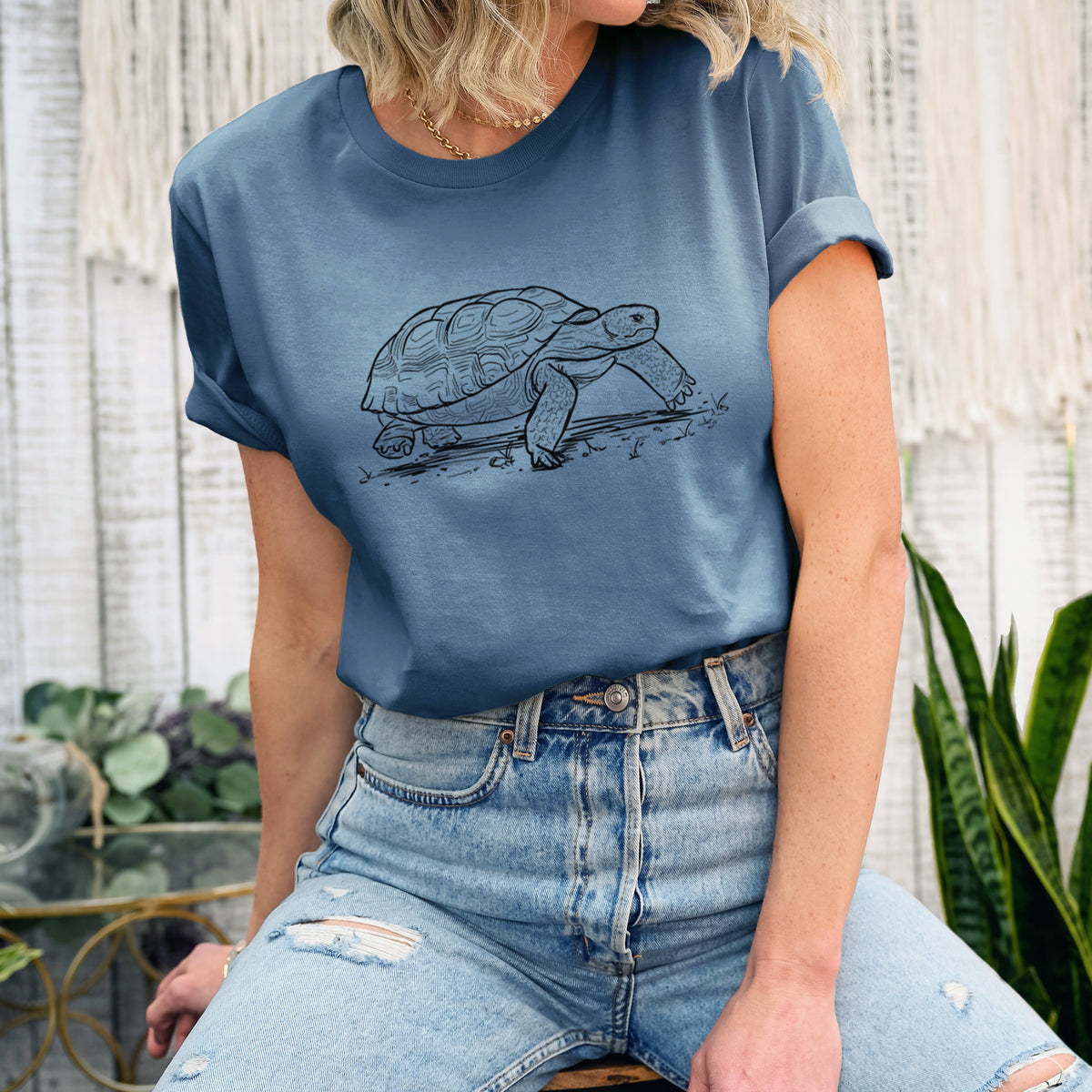 Woman wearing a steel blue lightweight cotton t-shirt printed with a detailed black ink illustration of a gopher tortoise walking.