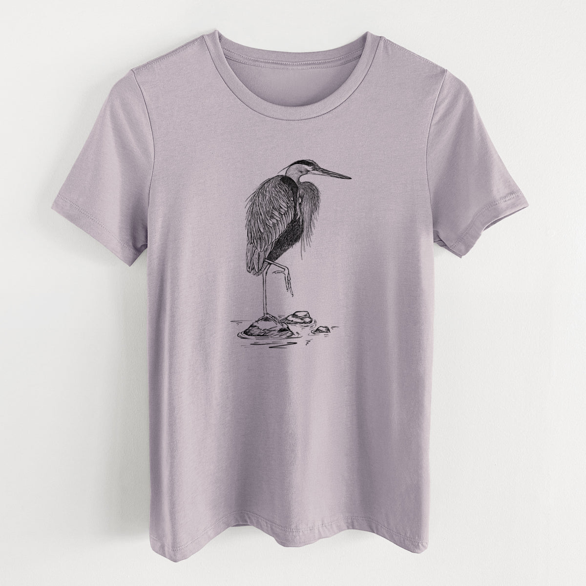 Light violet women's relaxed fit cotton t-shirt laid flat, printed with a detailed black ink illustration of a great blue heron standing on rocks.