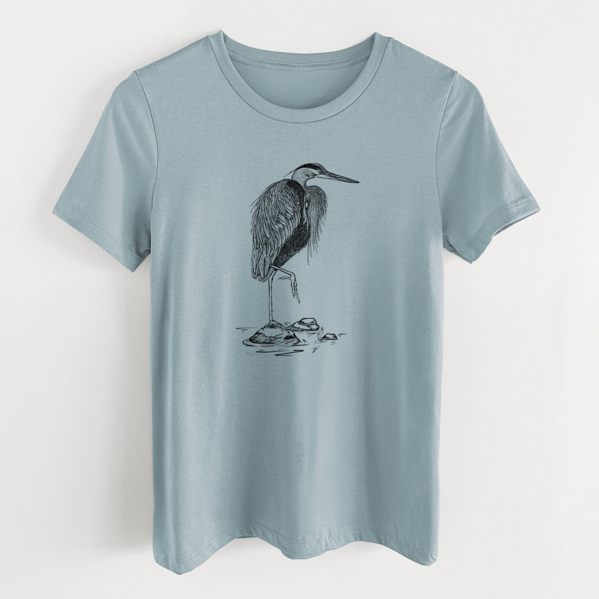 Vintage denim women's relaxed fit cotton t-shirt laid flat, printed with a detailed black ink illustration of a great blue heron standing on rocks.