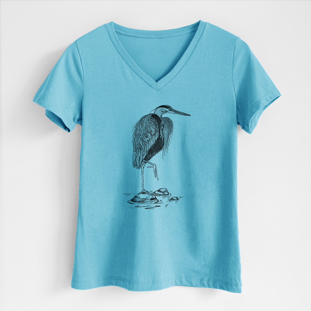 Turquoise women's relaxed fit cotton V-neck t-shirt laid flat, printed with a detailed black ink illustration of a great blue heron standing on rocks.
