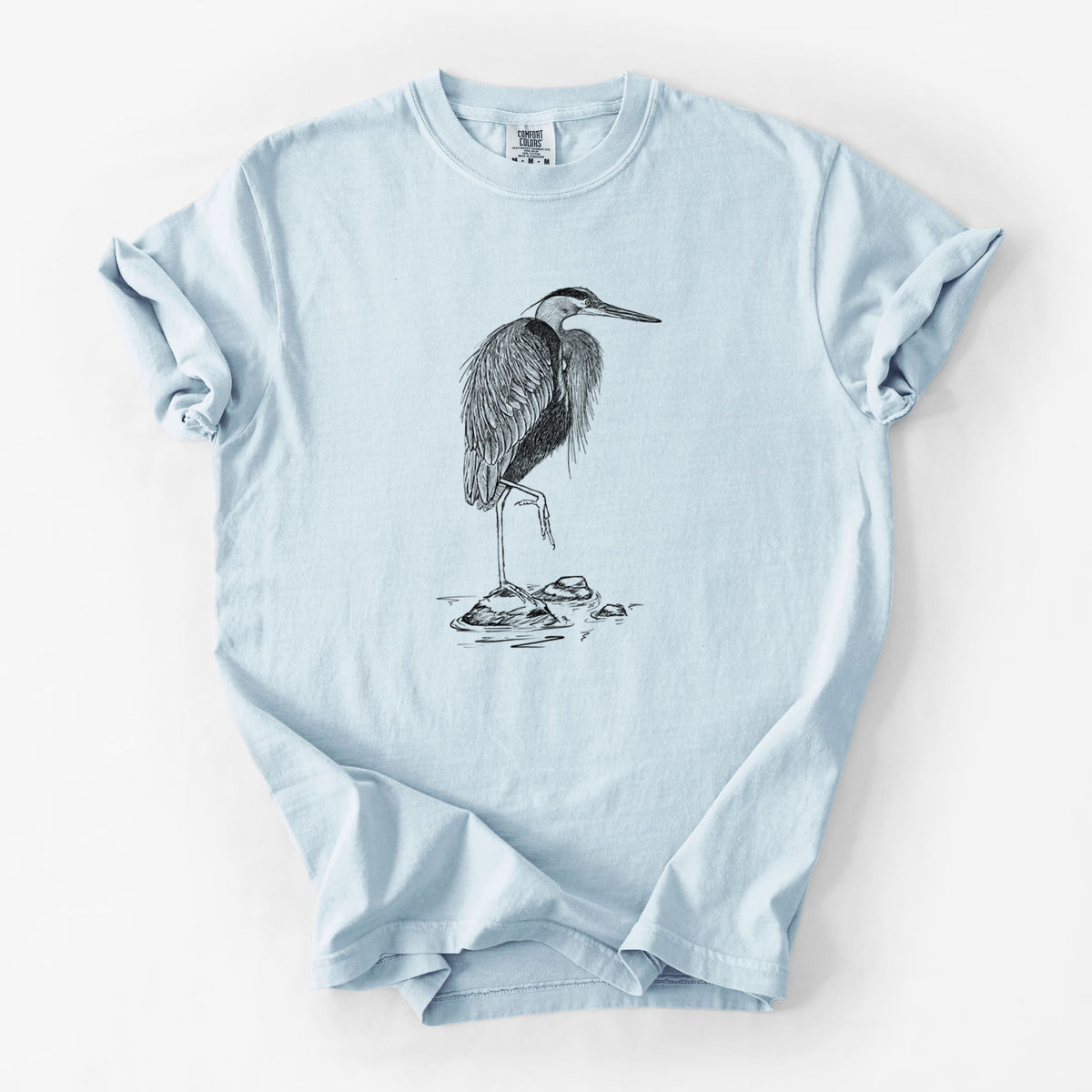 Chambray blue Comfort Colors t-shirt laid flat, printed with a detailed black ink illustration of a great blue heron standing on rocks.