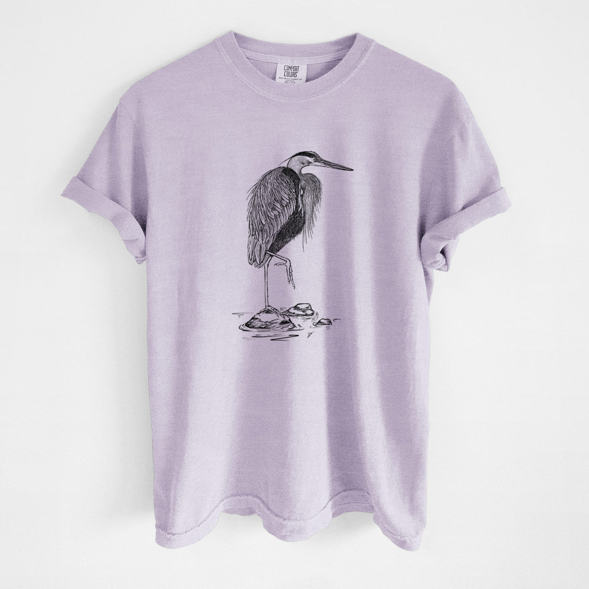 Orchid purple Comfort Colors t-shirt laid flat, printed with a detailed black ink illustration of a great blue heron standing on rocks.