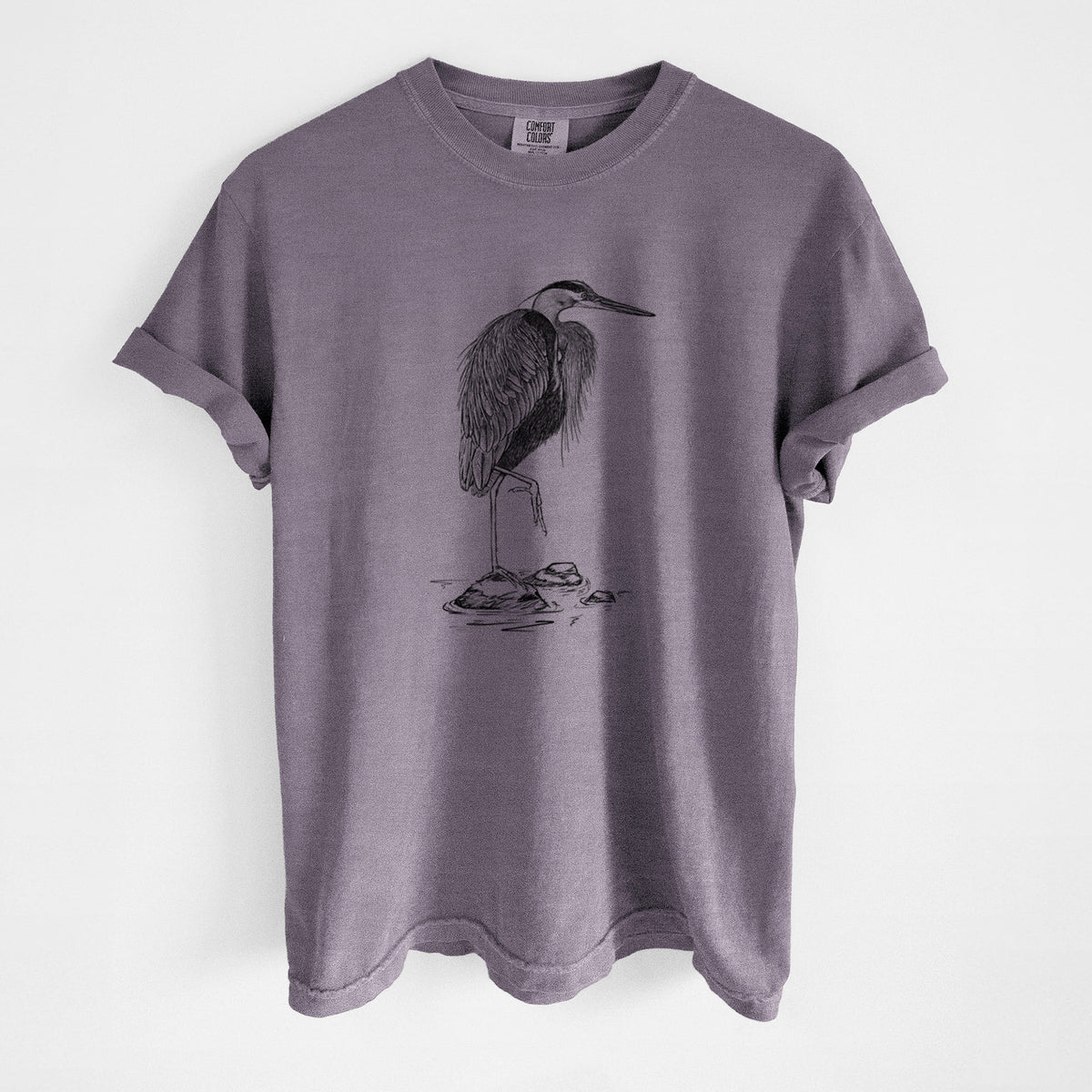 Wine red Comfort Colors t-shirt laid flat, printed with a detailed black ink illustration of a great blue heron standing on rocks.