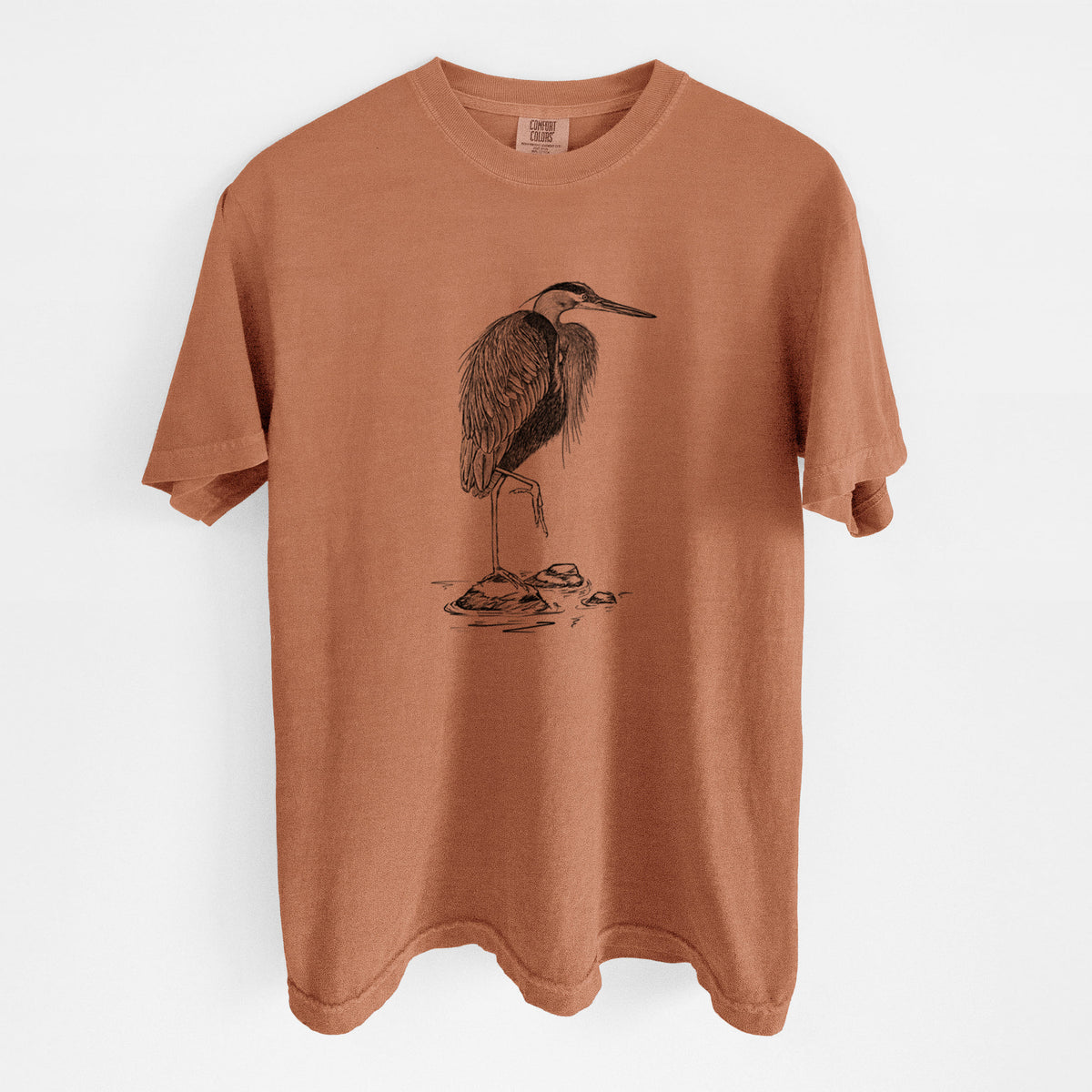 Yam burnt orange Comfort Colors t-shirt laid flat, printed with a detailed black ink illustration of a great blue heron standing on rocks.