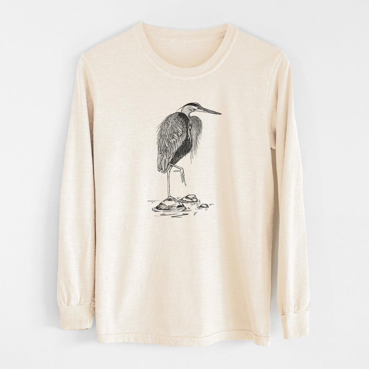 Ivory Comfort Colors long sleeve shirt laid flat, printed with a detailed black ink illustration of a great blue heron standing on rocks.