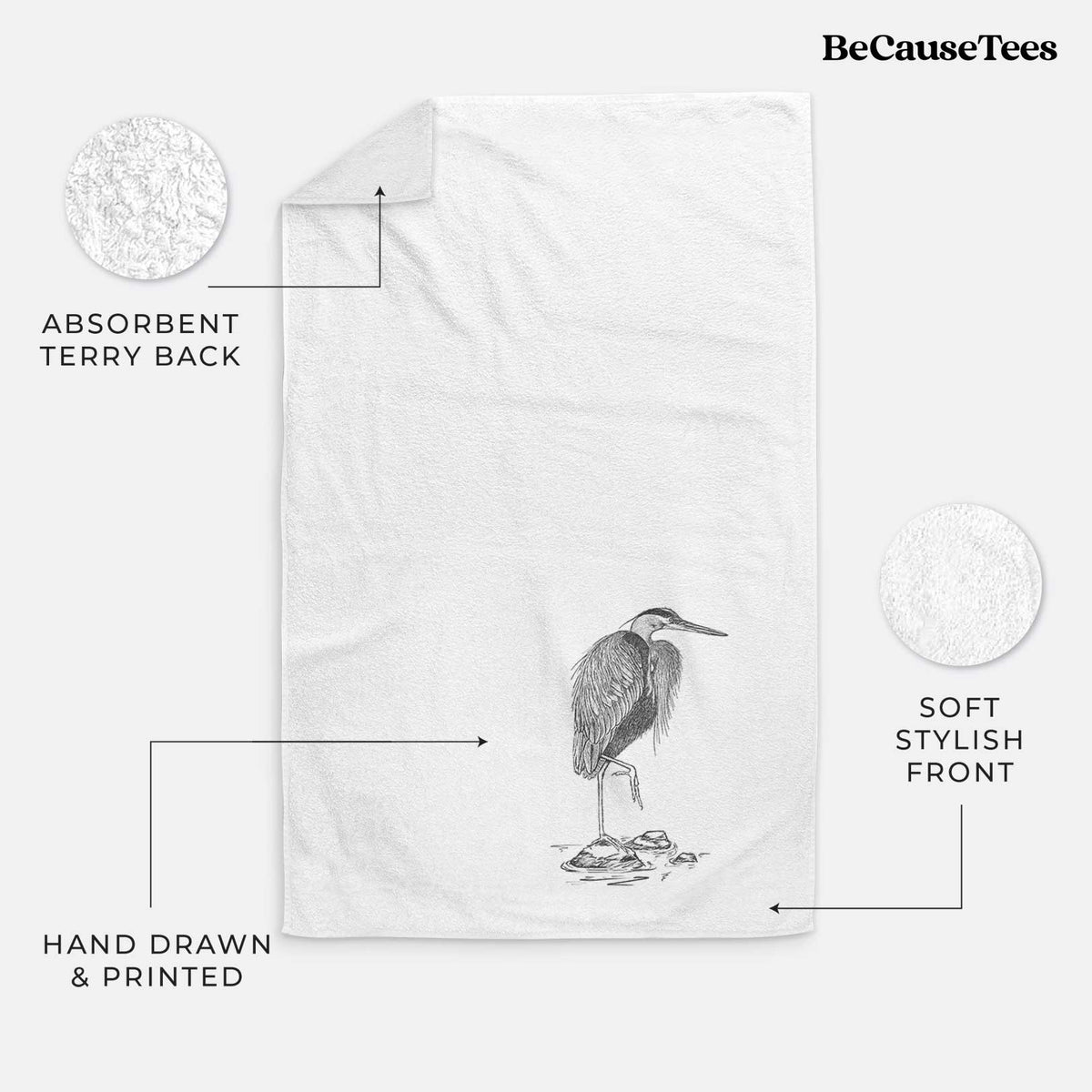 White hand towel printed with a detailed black ink illustration of a great blue heron standing on rocks.