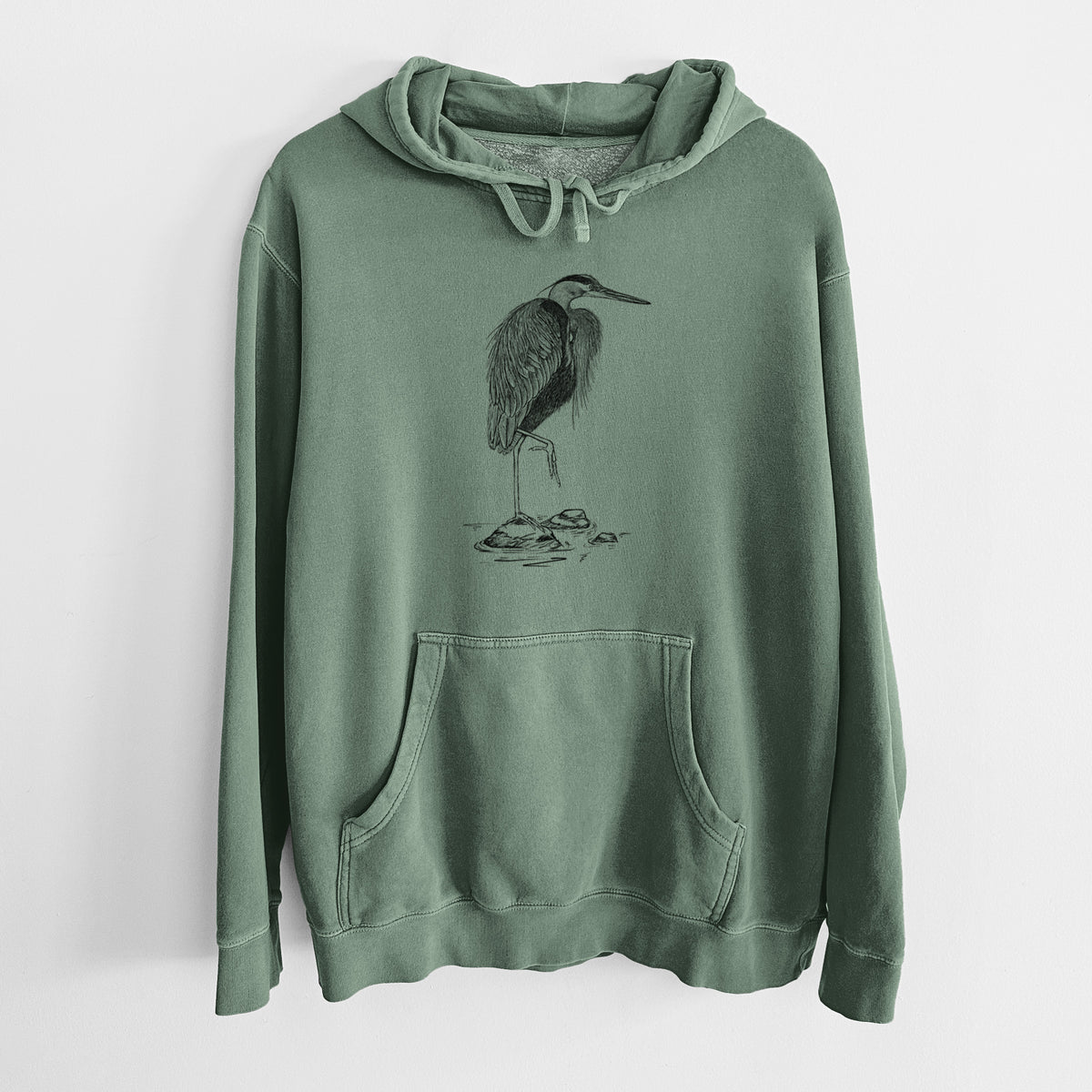 Alpine green pigment dyed hoodie laid flat, printed with a detailed black ink illustration of a great blue heron standing on rocks.