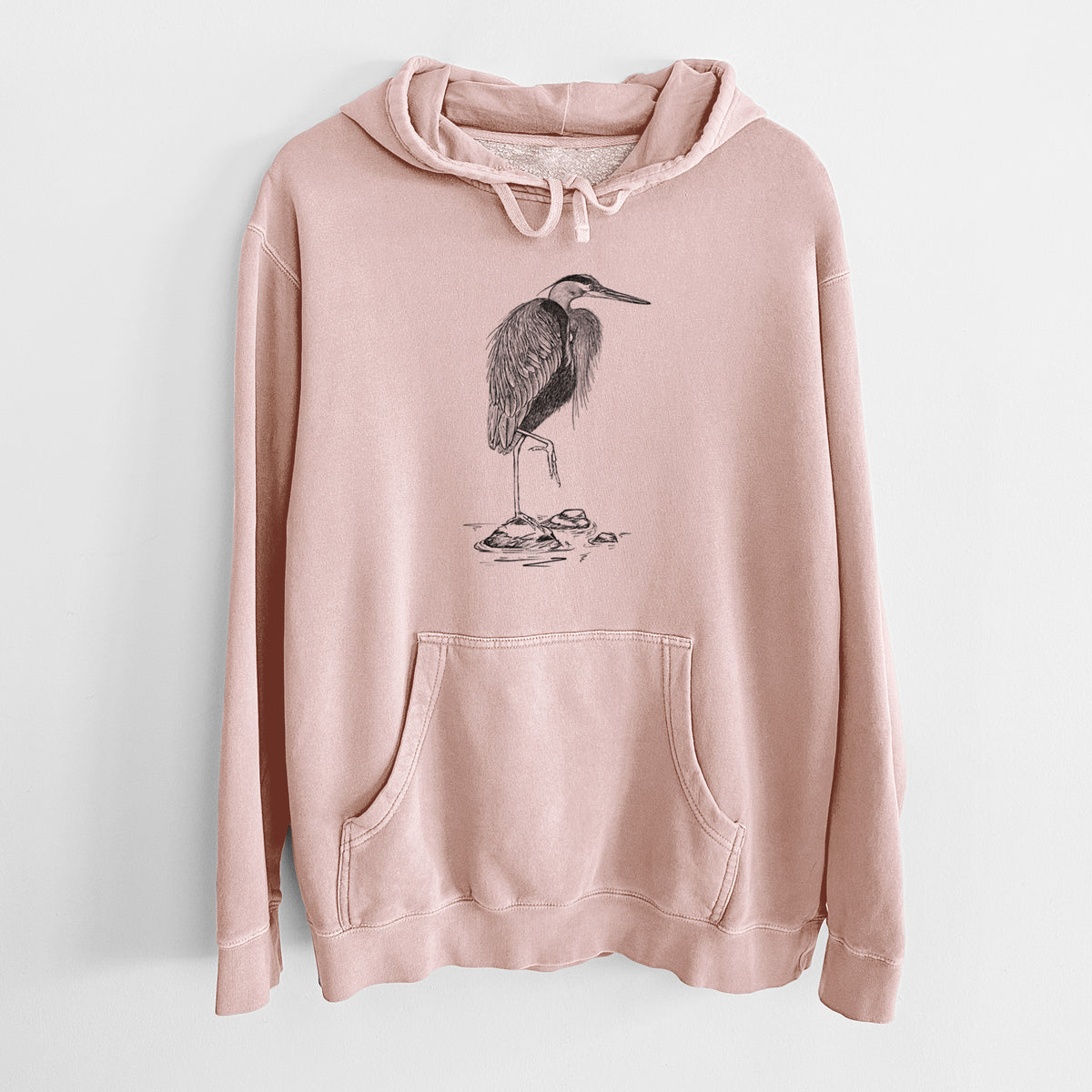 Dusty pink pigment dyed hoodie laid flat, printed with a detailed black ink illustration of a great blue heron standing on rocks.