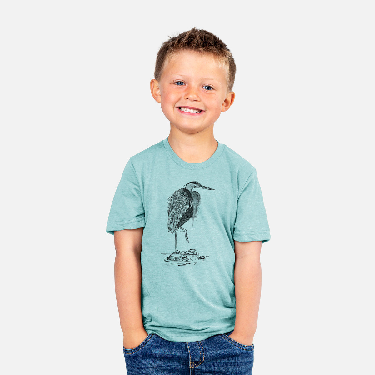 Smiling boy wearing a youth t-shirt printed with a detailed black ink illustration of a great blue heron standing on rocks.
