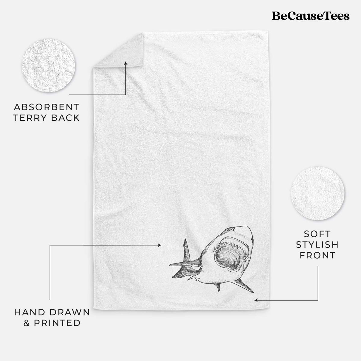 White hand towel printed with a black ink illustration of a great white shark swimming toward the viewer with its mouth open.
