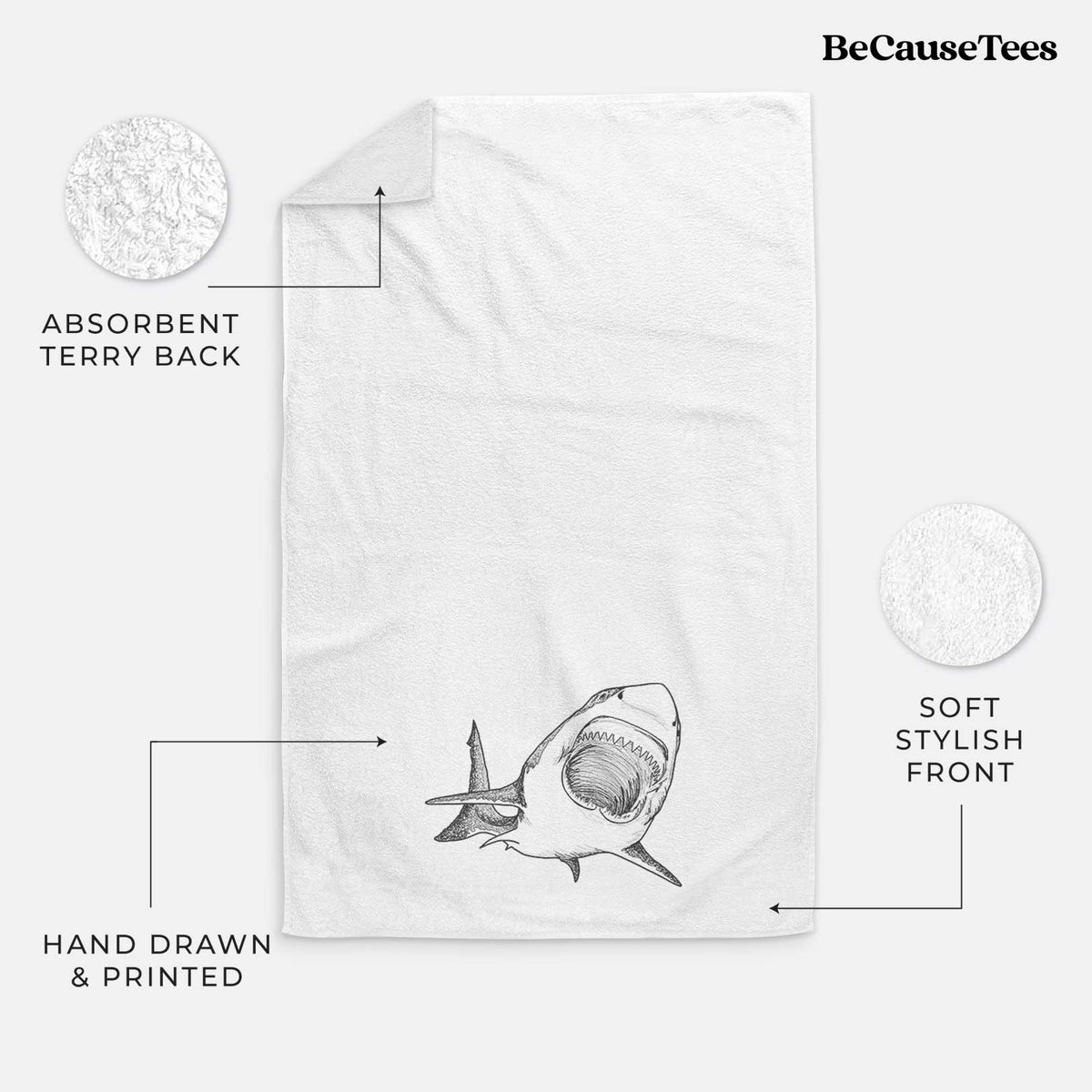 White hand towel printed with a black ink illustration of a great white shark swimming toward the viewer with its mouth open.
