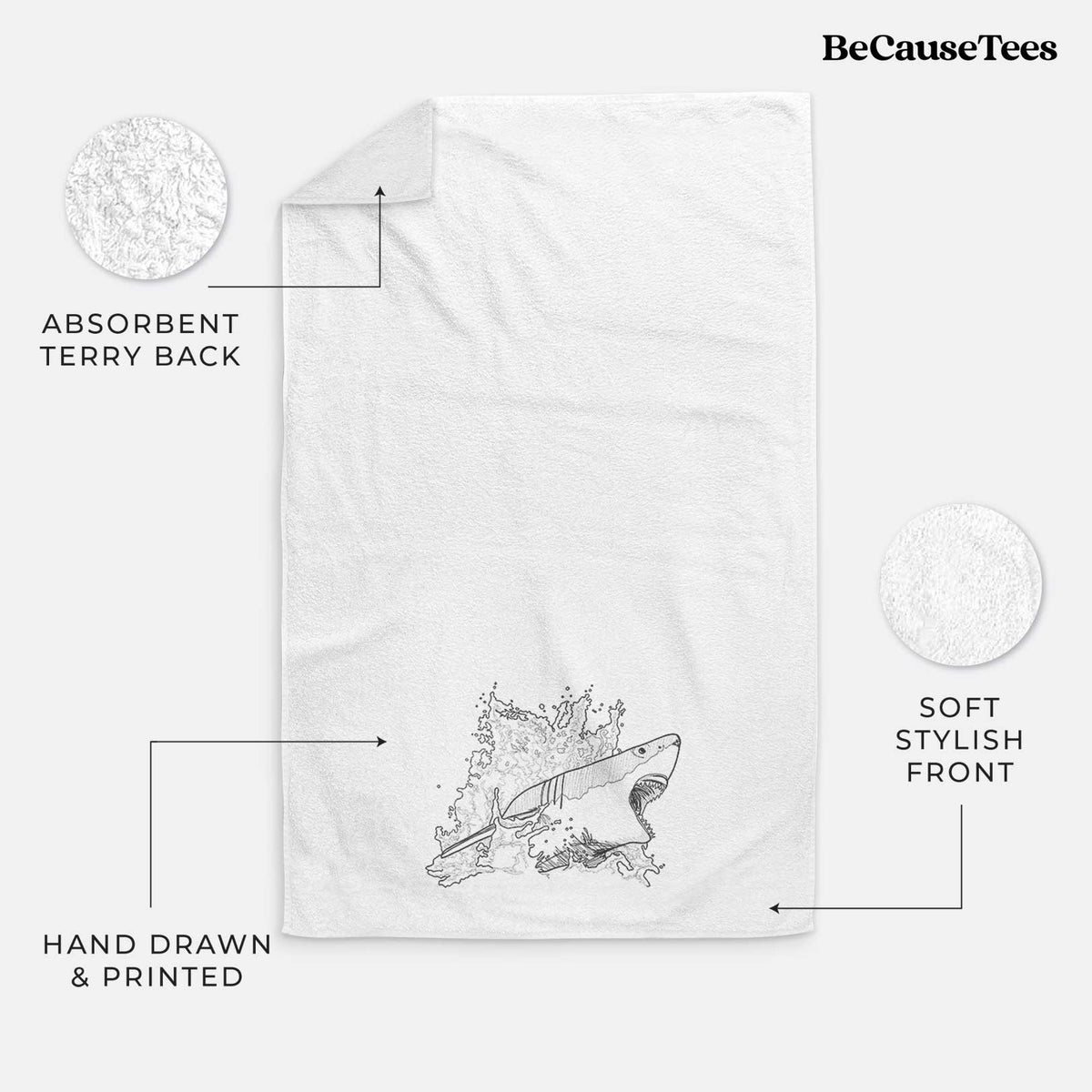 White hand towel printed with a black ink illustration of a great white shark breaking through a splash of water.