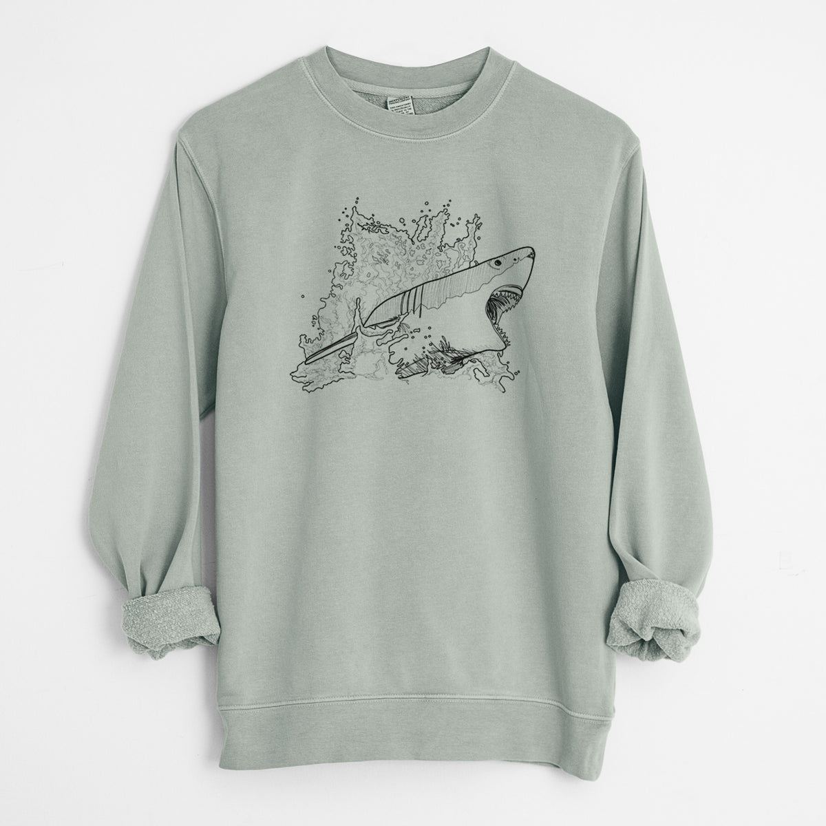 Sage green pigment dyed crewneck sweatshirt laid flat with the sleeves rolled, printed with a black ink illustration of a great white shark breaking through a splash of water.