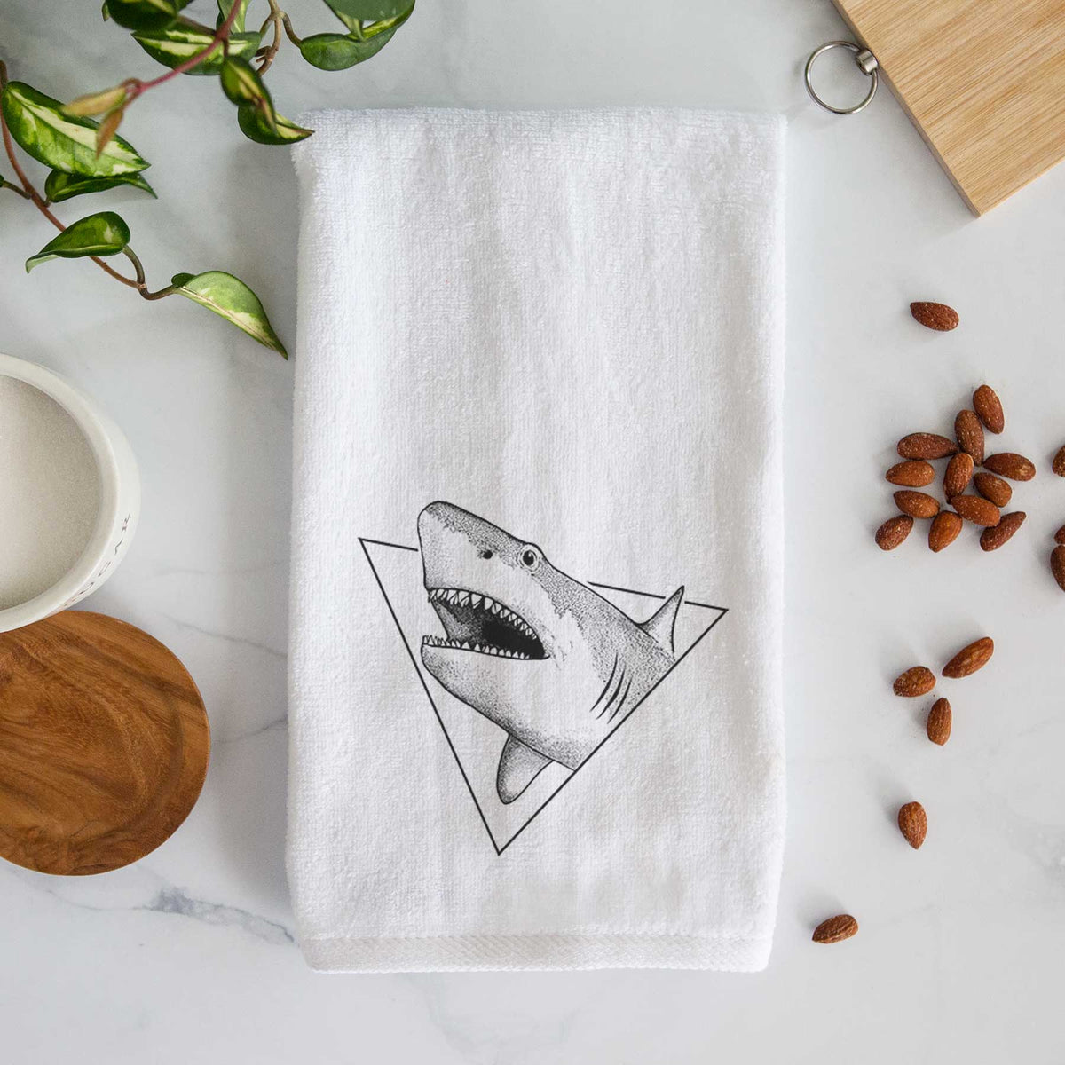 White hand towel printed with a black ink great white shark bursting out of a triangle outline with its mouth open.