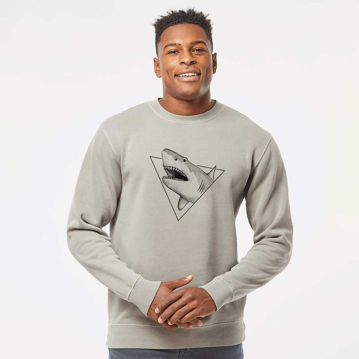 Model wearing a cement grey pigment dyed crewneck sweatshirt printed with a black ink great white shark bursting out of a triangle outline with its mouth open.
