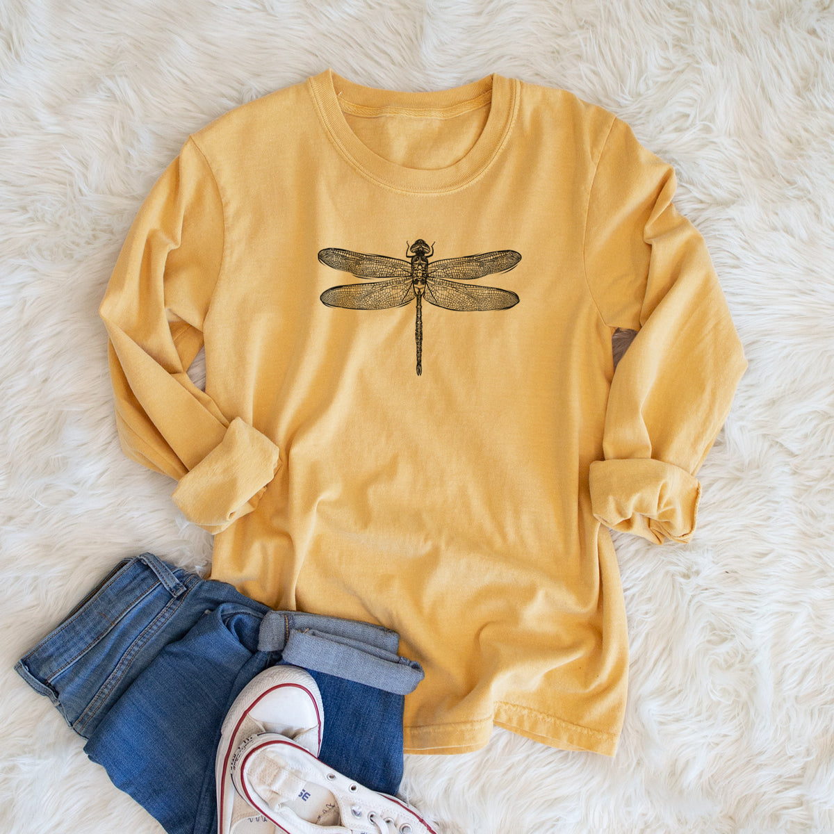 Golden wheat yellow Comfort Colors long sleeve shirt printed with a detailed black ink illustration of a green darner dragonfly with its wings spread, seen from above, shown in a lifestyle photo.