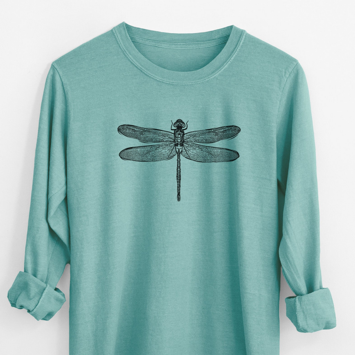 Reef green Comfort Colors long sleeve shirt laid flat with the cuffs rolled, printed with a detailed black ink illustration of a green darner dragonfly with its wings spread, seen from above.
