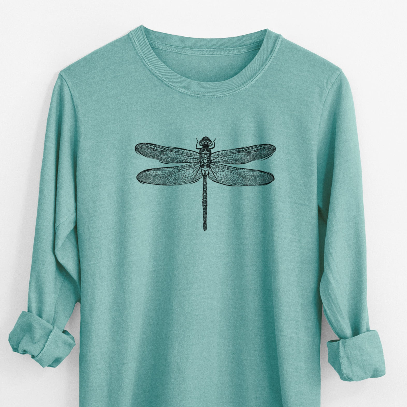 Reef green Comfort Colors long sleeve shirt laid flat with the cuffs rolled, printed with a detailed black ink illustration of a green darner dragonfly with its wings spread, seen from above.