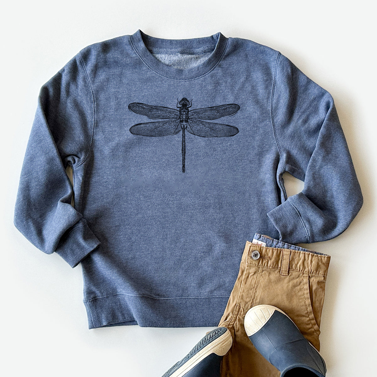 Youth crewneck sweatshirt printed with a detailed black ink illustration of a green darner dragonfly with its wings spread, seen from above, styled flat with khaki pants and shoes.