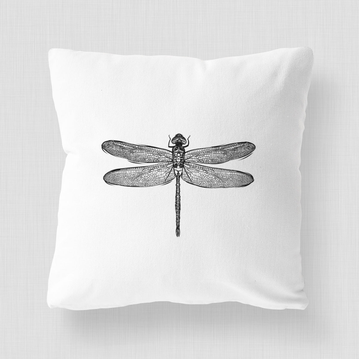 White pillow cover printed with a detailed black ink illustration of a green darner dragonfly with its wings spread, seen from above.