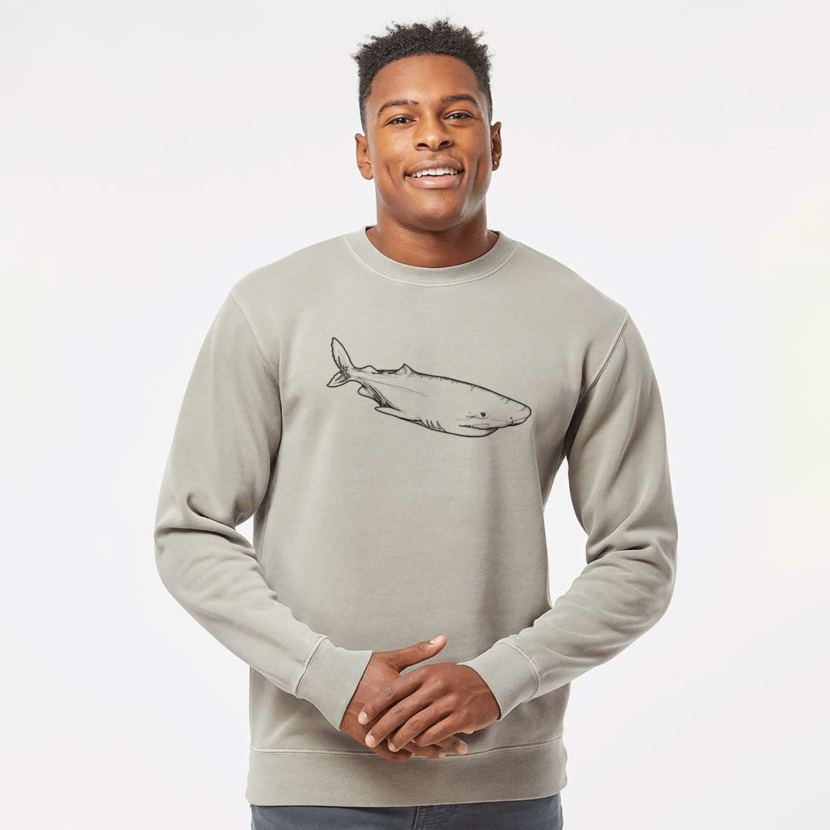 Model wearing a cement grey pigment dyed crewneck sweatshirt printed with a black ink illustration of a Greenland shark swimming.