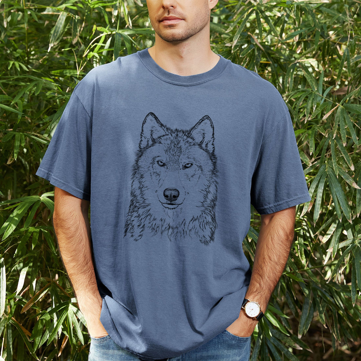 Man wearing a Comfort Colors t-shirt printed with a detailed black ink portrait of a grey wolf facing forward, outdoors.