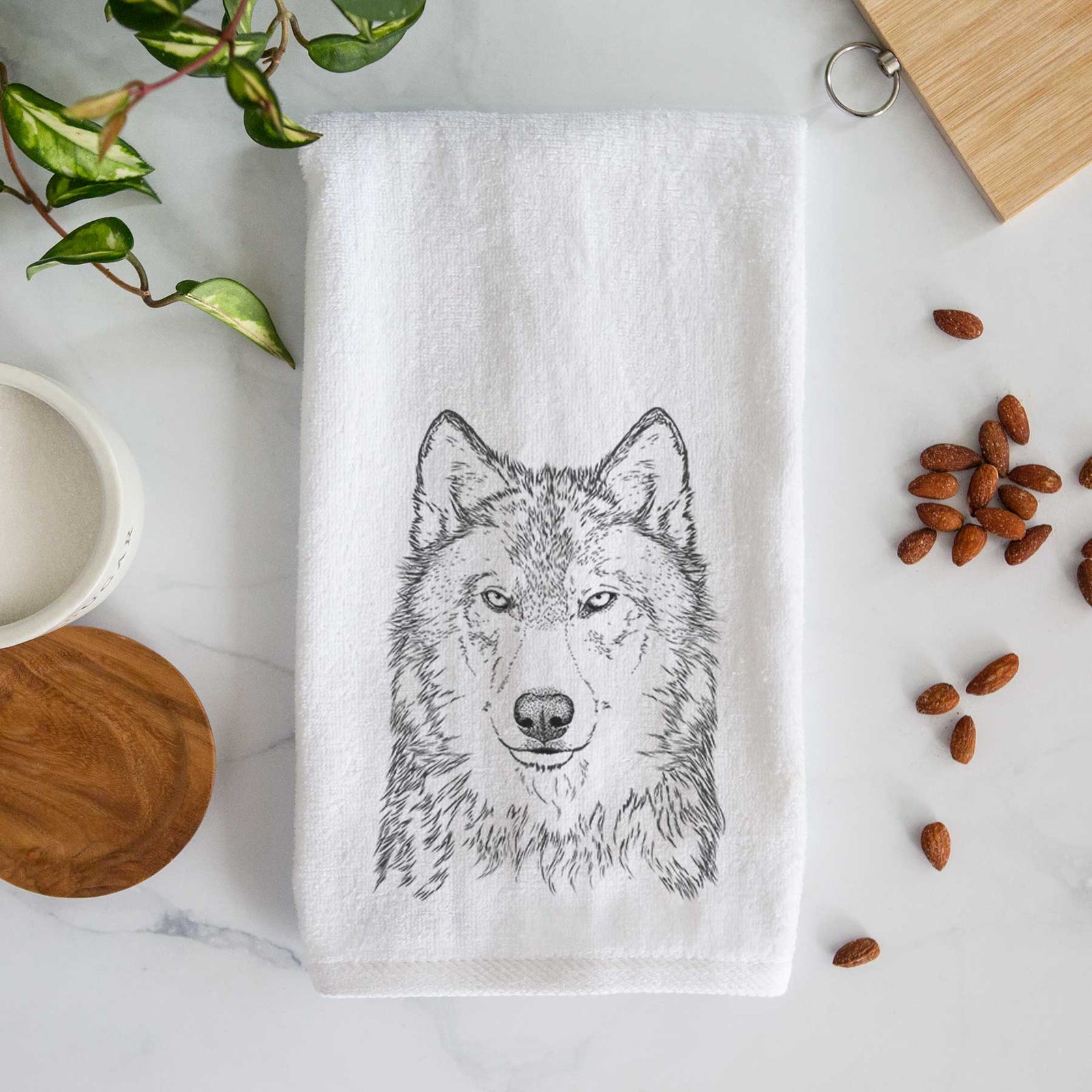White hand towel printed with a detailed black ink portrait of a grey wolf facing forward.